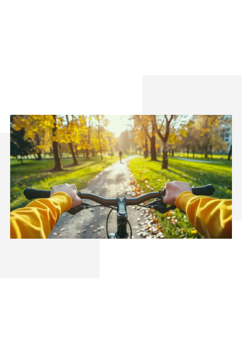 Person wearing a yellow jacket riding a bicycle on a sunlit path lined with autumn trees.